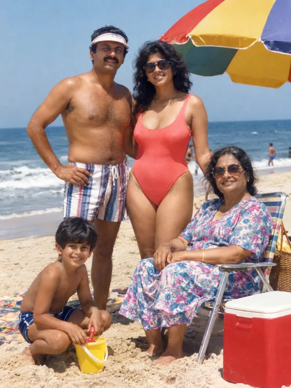 Family under a rainbow beach umbrella with a cooler and bucket on a 1980s summer holiday